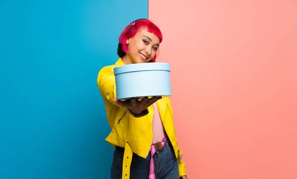 Young woman with yellow jacket holding a gift in hands