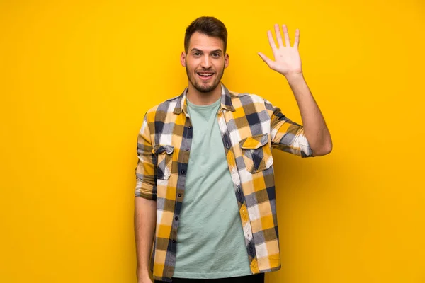 Knappe Man Gele Muur Die Met Hand Met Gelukkig Expressie — Stockfoto