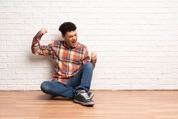 Junger Mann Sitzt Auf Dem Boden Und Feiert Einen Sieg — Stockfoto