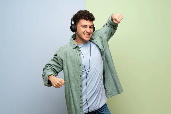 Mladý Muž Modré Zelené Pozadí Poslouchá Hudbu Sluchátky Tanec — Stock fotografie
