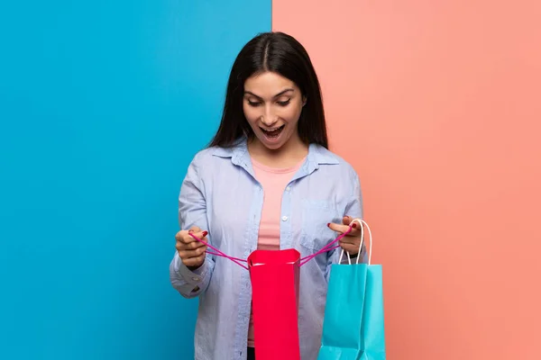 Jonge Vrouw Roze Blauwe Muur Verrast Terwijl Een Heleboel Boodschappentassen — Stockfoto