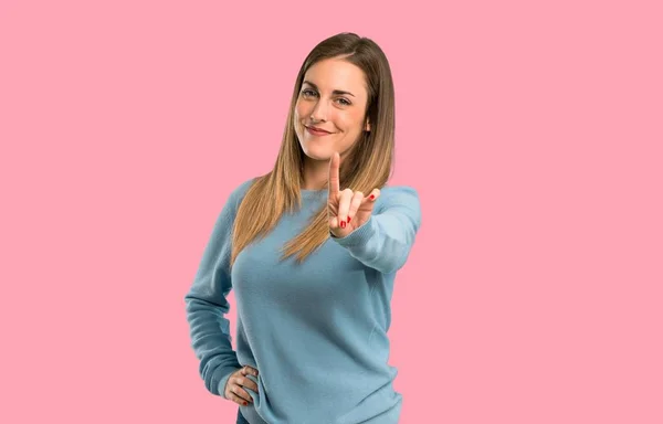 青いシャツを表示と分離ピンク背景に指を離すとブロンドの女性 — ストック写真