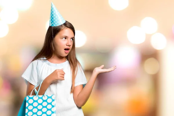 小女孩在生日聚会上拿着一个礼品袋, 对一些事情感到不开心和沮丧。无焦点背景下的负面面部表情 — 图库照片