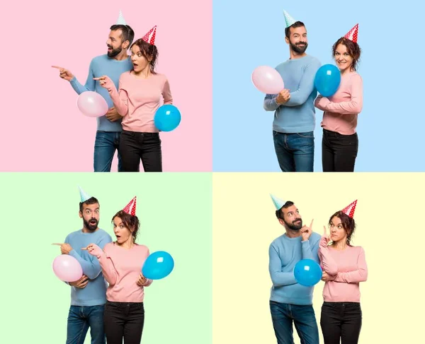 Set of couple with balloons and birthday hats keeping the arms crossed and pointing up and lateral