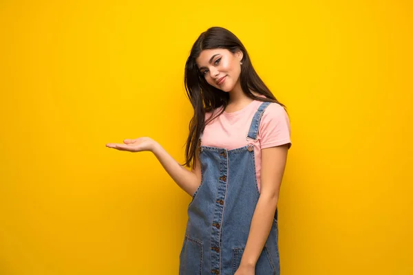 Adolescente Chica Sobre Amarillo Pared Presentando Una Idea Mientras Mira —  Fotos de Stock