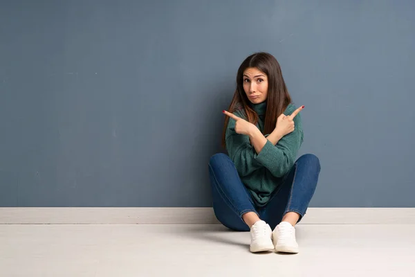 Junge Frau Sitzt Auf Dem Boden Und Zeigt Auf Die — Stockfoto