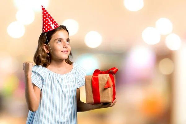 在生日聚会上举行的小女孩拿着礼物 在没有重点的背景下庆祝胜利 — 图库照片