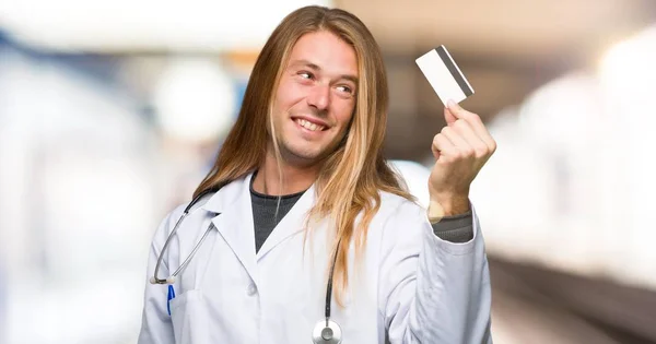 Doctor man holding a credit card and thinking in a hospital