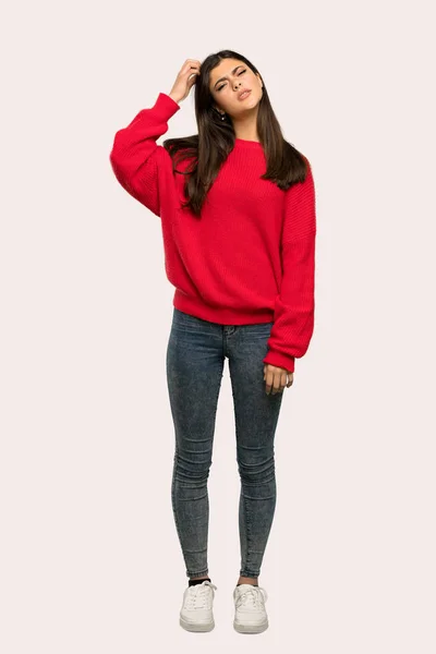分離の背景の上の頭を掻きながら疑問を持つ赤いセーターとティーンエイ ジャーの女の子のフルレングス ショット — ストック写真