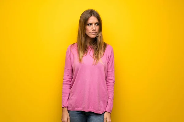 不調を感じる黄色の壁にピンクのセーターの女性 — ストック写真