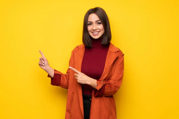 Mujer Joven Con Abrigo Apuntando Con Dedo Hacia Lado —  Fotos de Stock