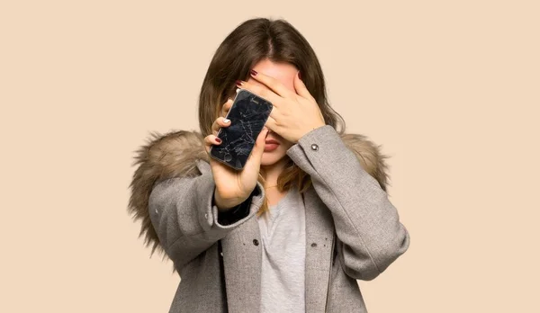 Menina Adolescente Com Casaco Chateado Com Telefone Quebrado Fundo Amarelo — Fotografia de Stock