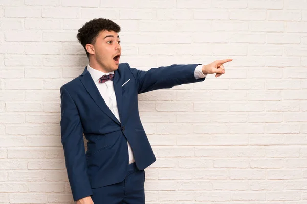 Man in suit and bow tie pointing away