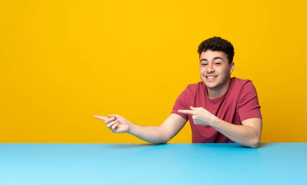 Jovem Com Parede Colorida Mesa Apontando Dedo Para Lado — Fotografia de Stock