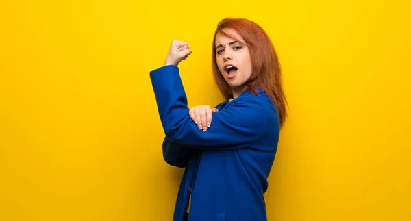 Young redhead woman with trench coat Doing strong gesture