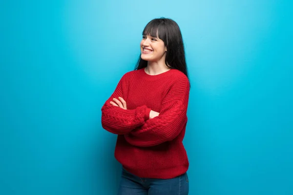 Woman with red sweater over blue wall Happy and smiling