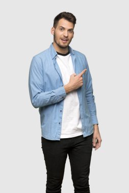 Yakışıklı adam şaşırmış ve işaret parmak tarafında gri arka plan üzerinde