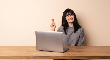 Onu laptop ile en iyi dilek ve geçiş parmakları ile çalışan genç kadın