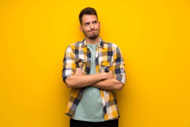 Yakışıklı adam omuz kaldırma sırasında sarı duvar yapım şüpheler jest