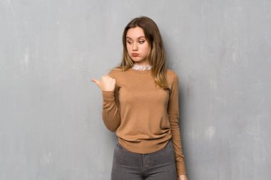 Genç kız yüzünden dokulu duvar mutsuz ve tarafa işaretleme