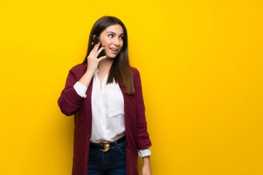 Cep telefonu ile bir konuşma tutmak sarı duvarın üzerinden genç kadın