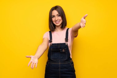 Sunulması ve el ile gelmek davet sarı duvarın üzerinden genç kadın