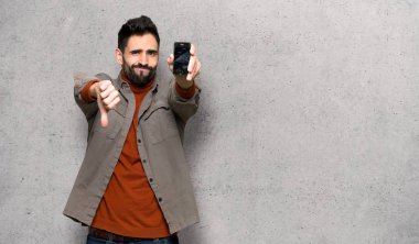 Kırık smartphone dokulu duvar'ın üstüne holding ile sakallı yakışıklı adam sorunlu