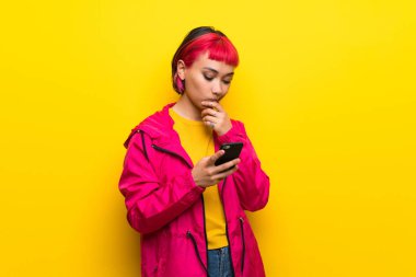 Düşünme ve ileti gönderme sarı duvarın üzerinden pembe saçlı genç kadın