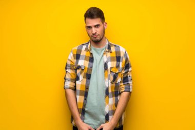 Yakışıklı adam üzgün ve depresyonda ifade ile sarı duvarın üzerinden