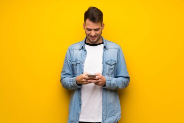 Yakışıklı adam sarı duvar mobil ileti gönderme