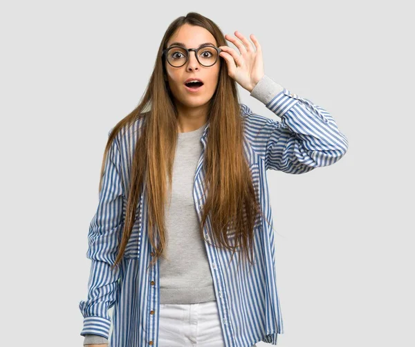メガネと孤立した灰色の背景上でびっくりのストライプのシャツを持つ少女 — ストック写真