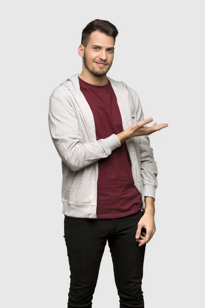 灰色の背景の上の方を探して笑顔ながらアイデアを提示のスエット シャツを持つ男 — ストック写真