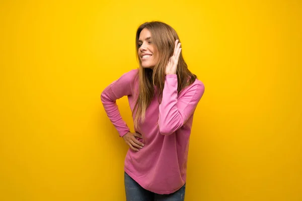 Vrouw Met Roze Trui Gele Muur Luisteren Naar Iets Door — Stockfoto