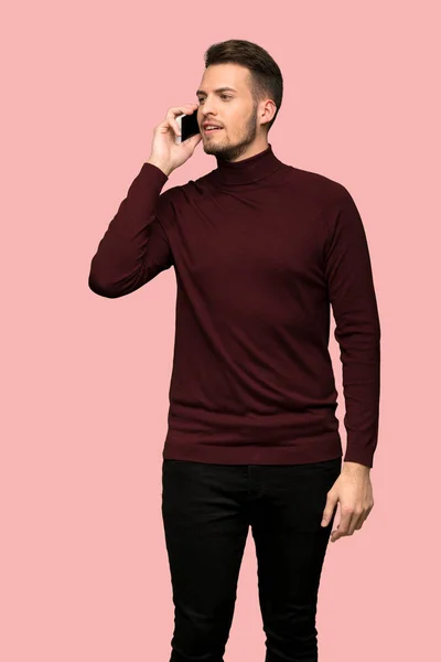Чоловік Жахливим Светром Тримає Розмову Мобільним Телефоном Рожевому Фоні — стокове фото