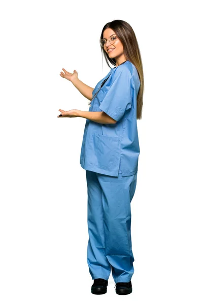 Cuerpo Completo Enfermera Joven Señalando Hacia Atrás Presentando Producto — Foto de Stock