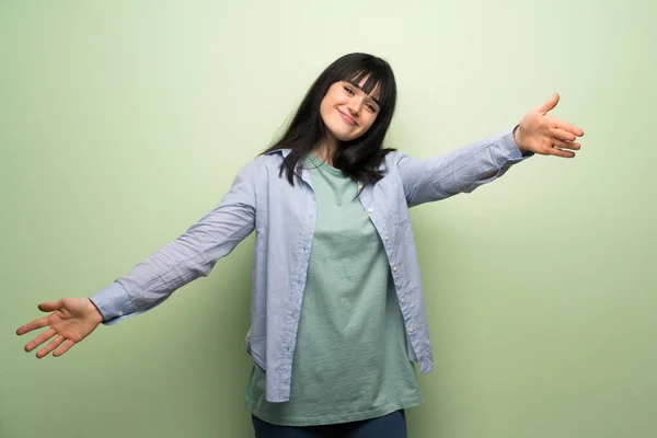 Young Woman Green Wall Presenting Inviting Come Hand — Stock Photo, Image