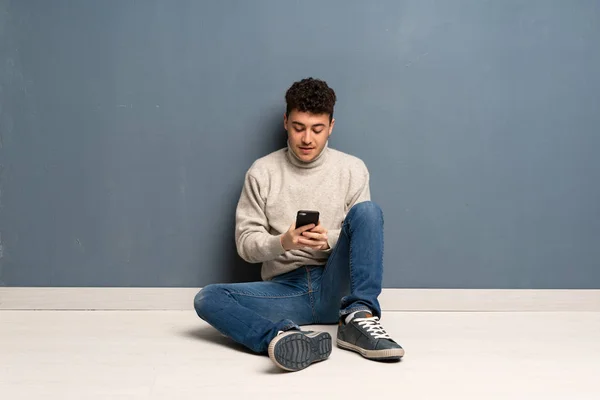 Junger Mann Sitzt Auf Dem Boden Und Sendet Eine Nachricht — Stockfoto