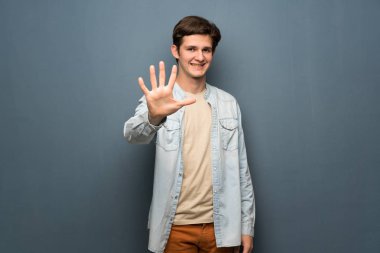 Jean ceket gri duvar beş parmak ile sayma üzerinde olan genç adam