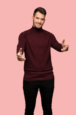 Adam sunulması ve pembe arka plan üzerinde el ile gelmek davet balıkçı yaka kazak