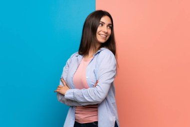 Genç kadın kolları olan pembe ve mavi duvarın üzerinden geçti