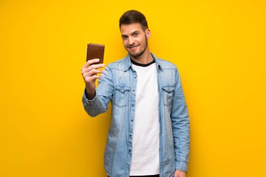 Bir cüzdan tutan sarı duvarın üzerinden yakışıklı adam
