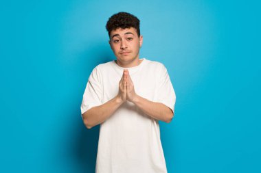 Mavi arka plan üzerinde genç adam birlikte palm tutar. Kişi için bir şey sorar