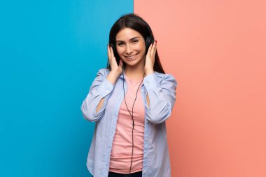 Pembe ve mavi duvar kulaklık ile müzik dinlemek genç kadın