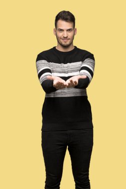 Sarı arka plan üzerinde bir reklam eklemek yakışıklı adam boşaltmak hayali avuç içinde tutan