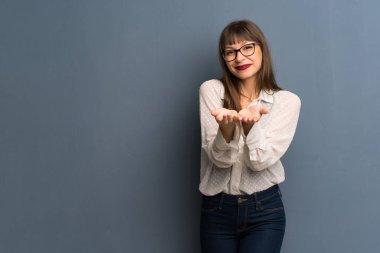 Kadın gözlük boşaltmak hayali avuç içinde tutan mavi duvarın üzerinden bir reklam eklemek için