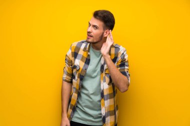 Bir şey kulak el koyarak dinleme sarı duvarın üzerinden yakışıklı adam