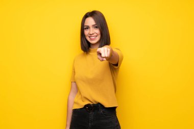 Genç kadın sarı duvarın üzerinden parmak seni kendinden emin bir ifadesiyle işaret