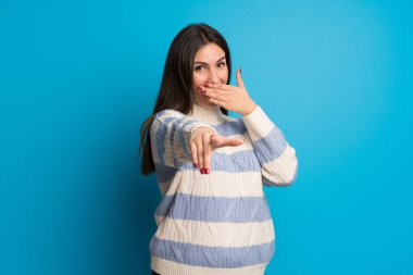 Birisi parmak ile işaret ve gülerek mavi duvarın üzerinden genç kadın