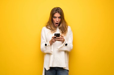 Sarışın kadın şaşırttı ve ileti gönderme sarı duvarın üzerinden