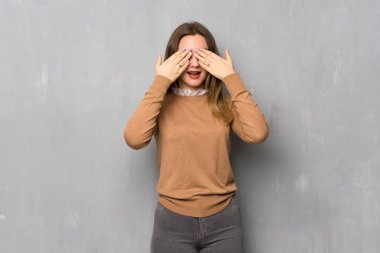 Genç kız dokulu duvar eller tarafından gözleri kaplama üzerinde. İleride ne olduğunu görmek için sürpriz